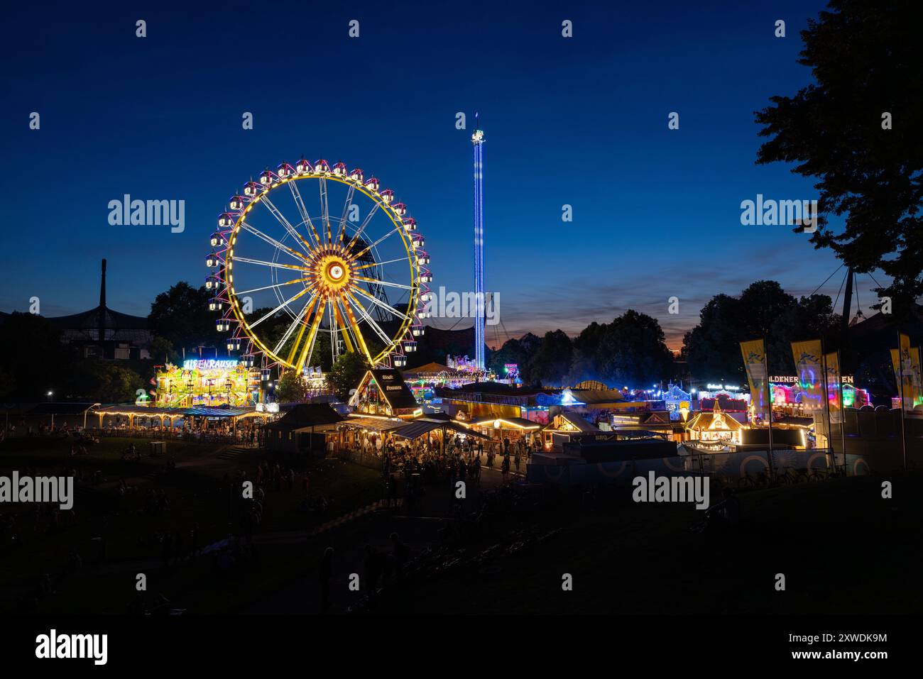 11. August 2024 - München, DEUTSCHLAND: Die Sommermesse im Olympiagebiet mit Riesenrad und anderen Messeattraktionen und lustigen Fahrgeschäften. Stockfoto