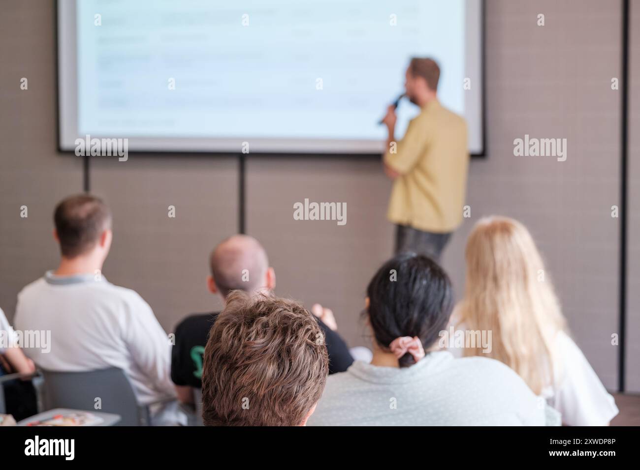 Referent präsentiert Sitzpublikum während einer Geschäftskonferenz oder eines Seminars. Die Teilnehmer achten auf die Präsentation im professionellen Umfeld. Stockfoto