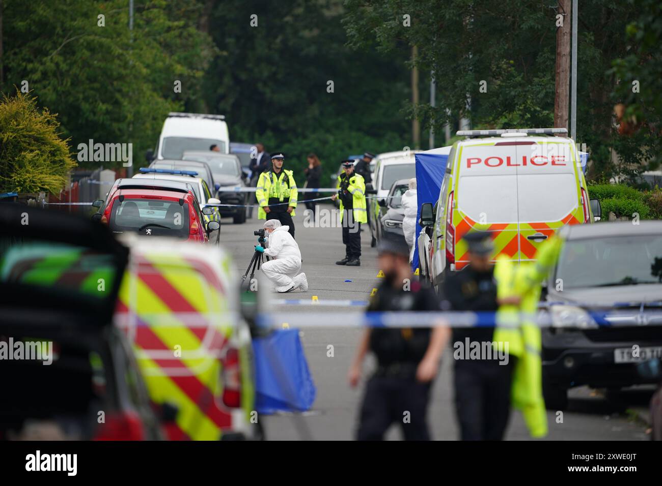 Gerichtsmediziner in der Nähe eines Anwesens in der Barnard Road in Gorton, Manchester, wo am Sonntagabend drei Personen mit schweren Stichverletzungen gerufen wurden. Eine 43-jährige Frau starb am Tatort, und ein 17-jähriges Mädchen und ein 64-jähriger Mann werden im Krankenhaus behandelt. Ein 22-jähriger Mann wurde wegen Mordverdacht verhaftet. Bilddatum: Montag, 19. August 2024. Stockfoto