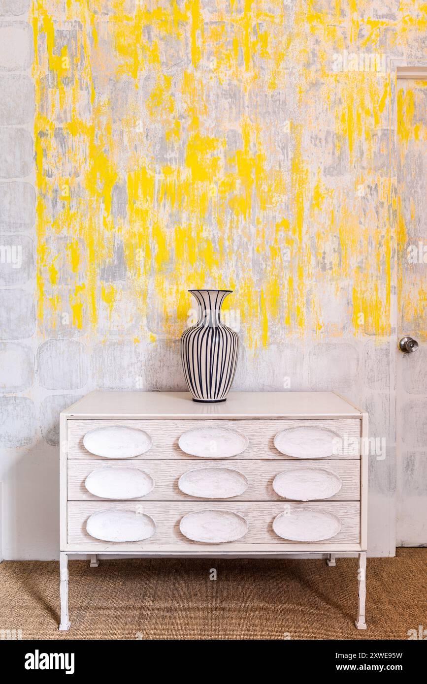 Gelber Abstrakt über Vase auf der Brust mit skulpturalen Griffen in der Atelierwohnung des britischen Designers Gareth Smith. South West London, Großbritannien Stockfoto