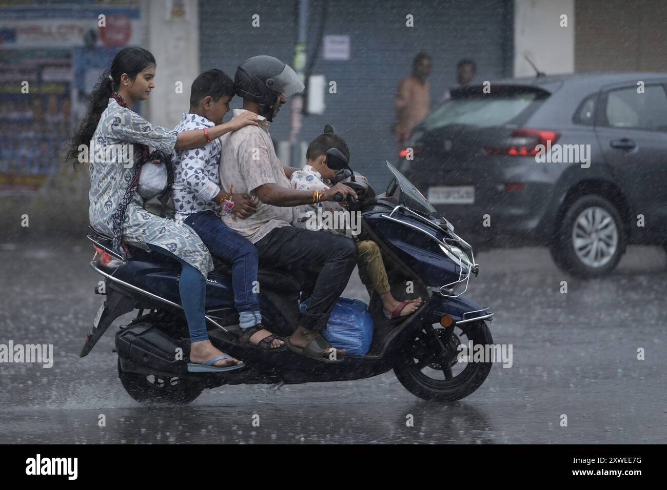 People ride a motorcycle in the rain in Hyderabad, India, Monday, Aug. 19, 2024. (AP Photo/Mahesh Kumar A.) Stockfoto