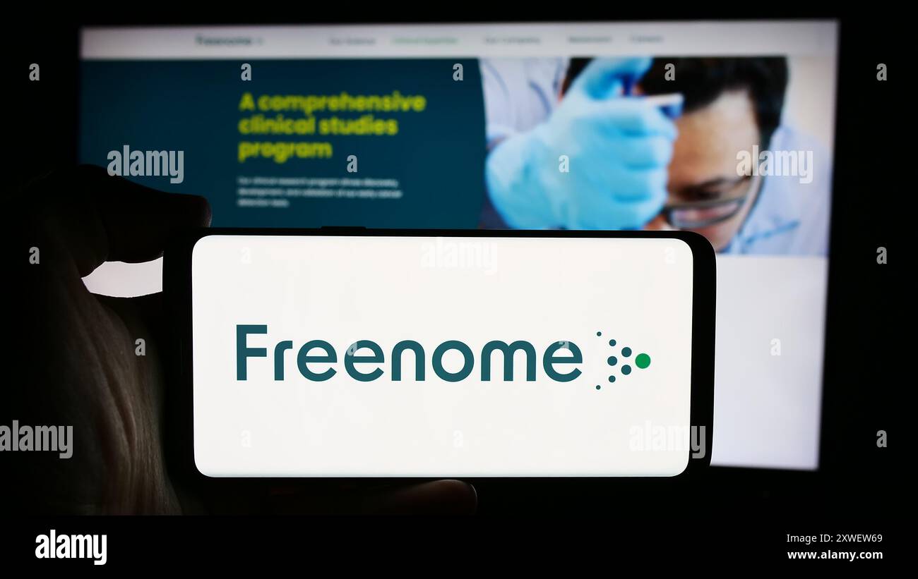 Person, die ein Mobiltelefon mit dem Logo des US-amerikanischen Biotechnologie-Unternehmens Freenome Holdings Inc. Vor der Webseite des Unternehmens hält. Schwerpunkt auf dem Display des Telefons. Stockfoto