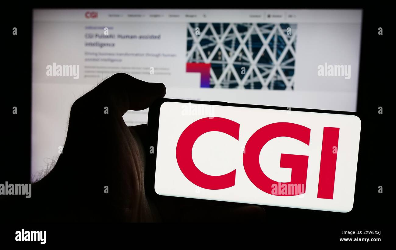Person, die ein Mobiltelefon mit dem Logo des kanadischen IT-Unternehmens CGI Inc. Vor der Business-Webseite hält. Schwerpunkt auf dem Display des Telefons. Stockfoto