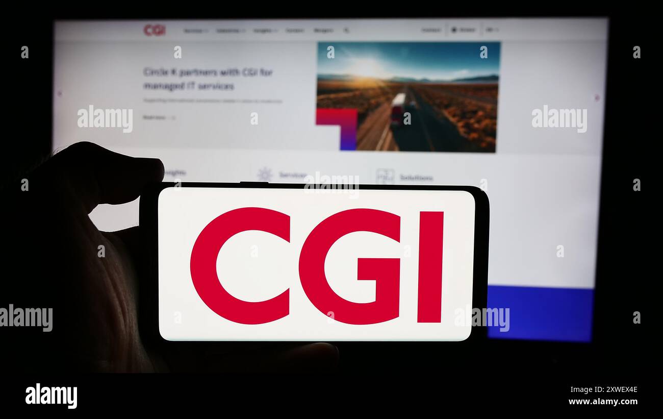 Person, die ein Mobiltelefon mit dem Logo des kanadischen IT-Unternehmens CGI Inc. Vor der Business-Website hält. Schwerpunkt auf dem Display des Telefons. Stockfoto