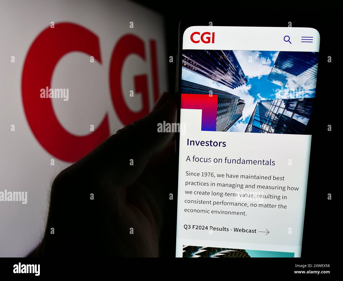 Person, die ein Mobiltelefon hält, mit der Webseite des kanadischen IT-Unternehmens CGI Inc. Vor dem Logo. Konzentrieren Sie sich auf die Mitte des Telefondisplays. Stockfoto