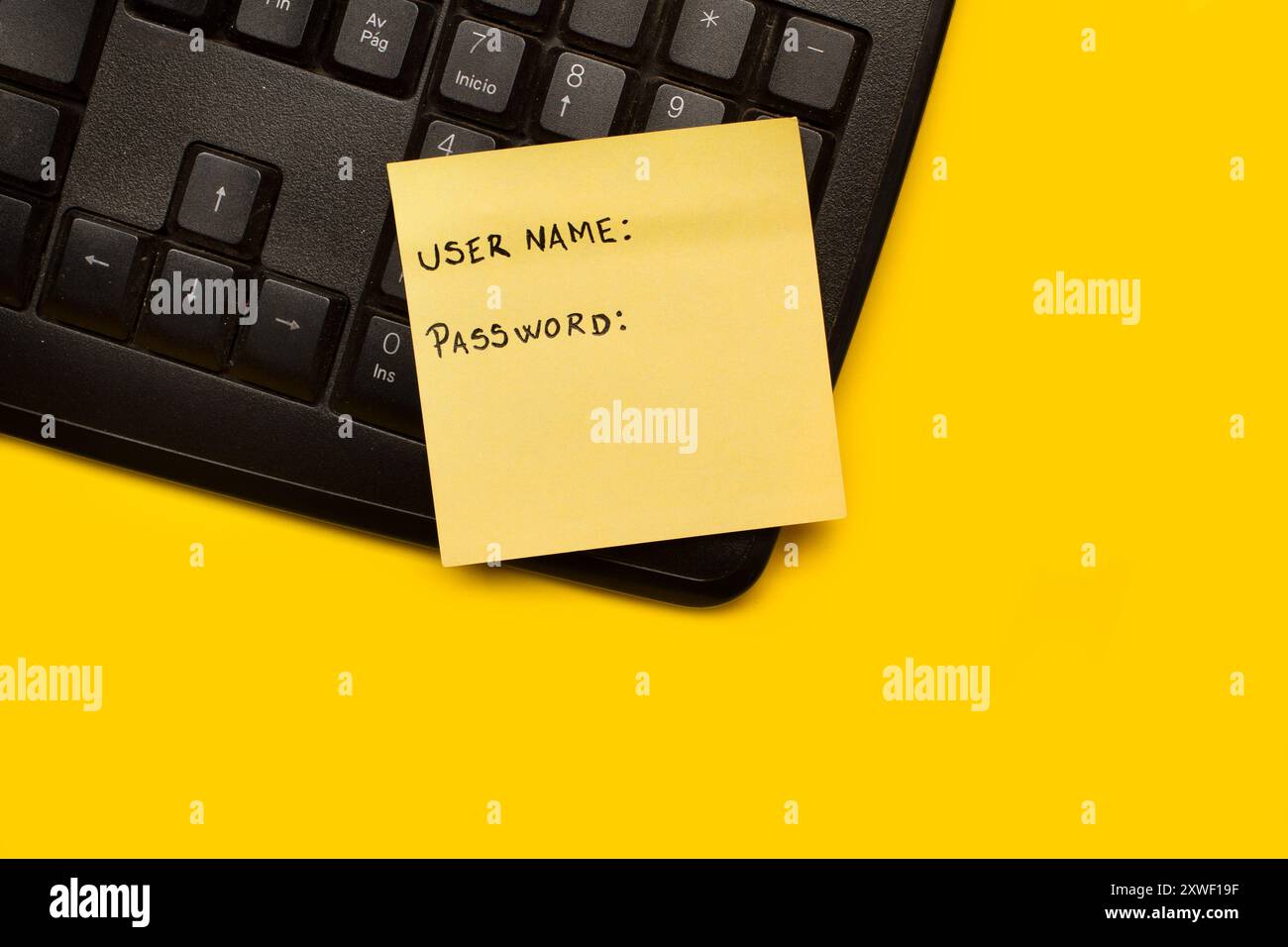 Eine gelbe Papiernotiz mit Benutzername und Kennwortwort auf einer schwarzen Computertastatur auf gelbem Hintergrund Stockfoto