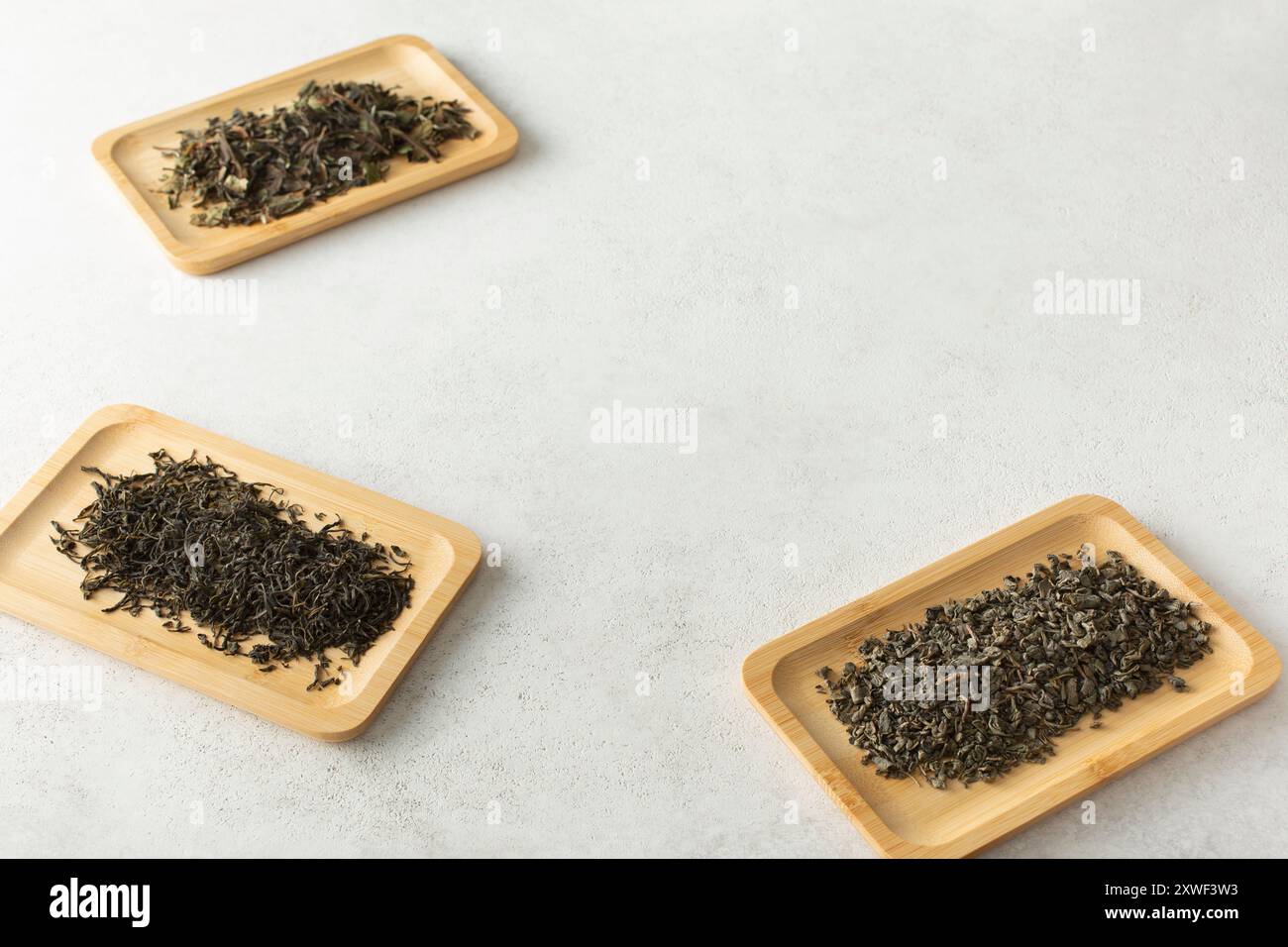 Eine Ansicht von verschiedenen losen Teeblättern auf Bambustabletts am Rand des Rahmens. Stockfoto