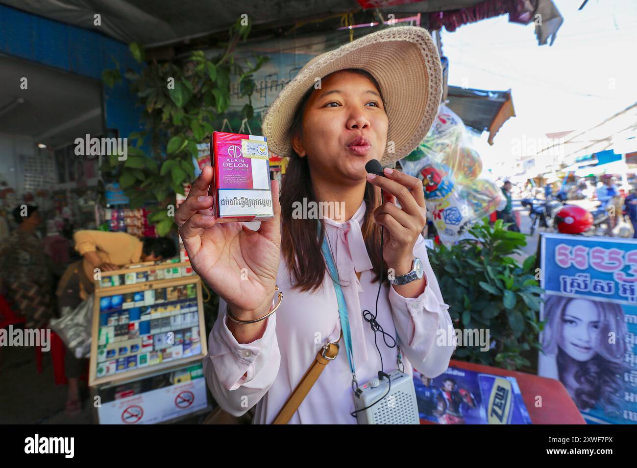 Phnom Penh, Kambodscha. 18. August 2024: Ein kambodschanischer Reiseleiter zeigt einer Gruppe von Touristen in Phnom Penh eine Packung Alain Delon Zigaretten. Der berühmte französische Schauspieler, international bekannt, starb heute. Er hinterlässt ein bedeutendes Erbe an Marken und Unternehmen, das sein Vermögen dank seines internationalen Einflusses machte. Diese beliebte Marke in Asien, die bis 2018 von British American Tobacco vermarktet wurde, war bis 2020 noch auf asiatischen Märkten mit den Slogans „A Taste of France“ & „Signature Taste“ erhältlich. Einige Fremdenführer oder Zigarettenverkäufer haben die Verpackungen als Sammlerstücke aufbewahrt. Quelle: Kevin Izorce/Alamy Live News Stockfoto