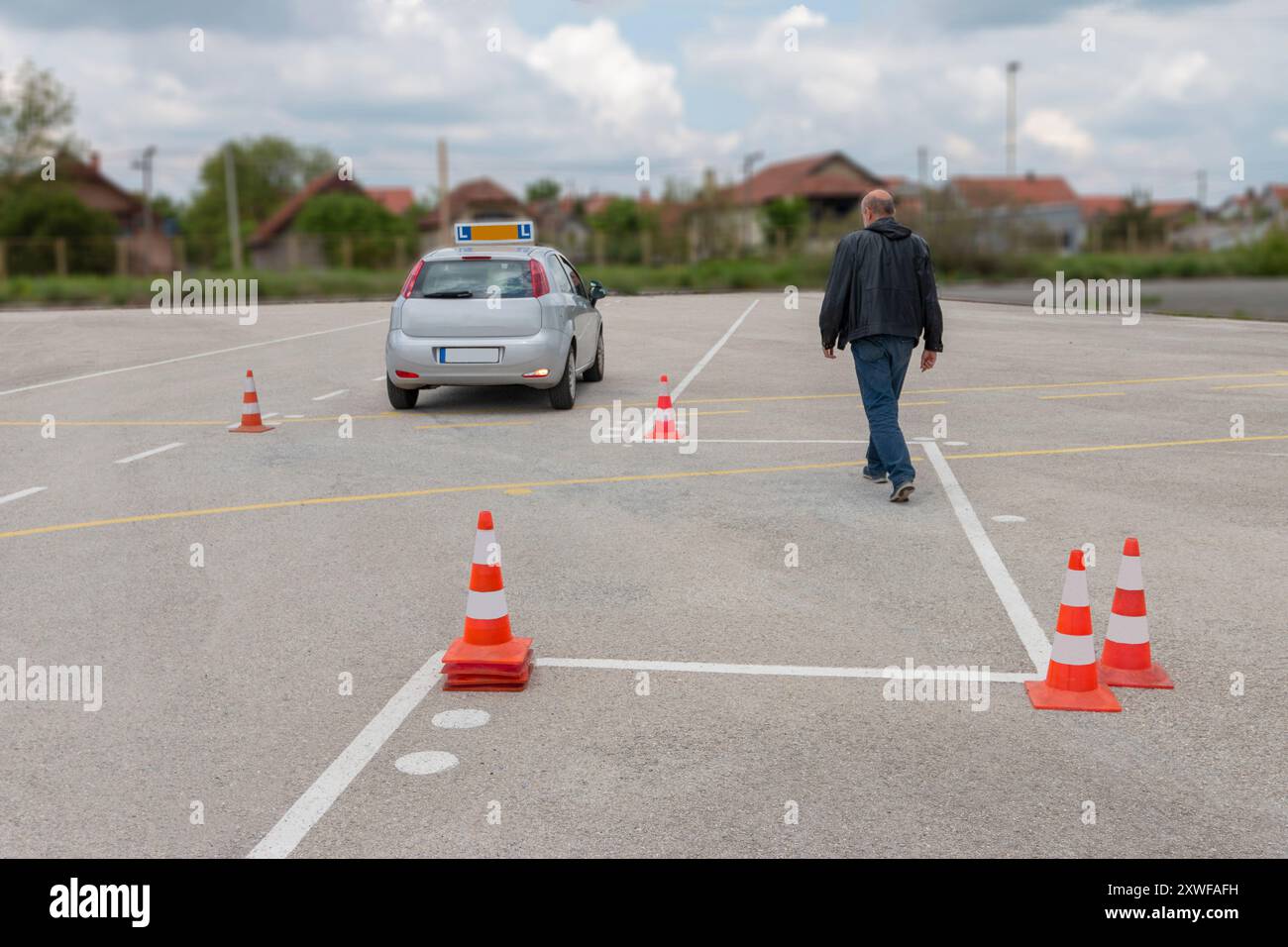 Das Mädchen übt das Parken auf dem Polygon, während ihr Lehrer sie von draußen beobachtet. Stockfoto
