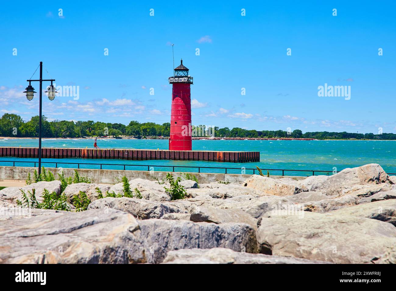 Red Lighthouse am Pier mit Felsen und Grün - Blick auf Augenhöhe Stockfoto