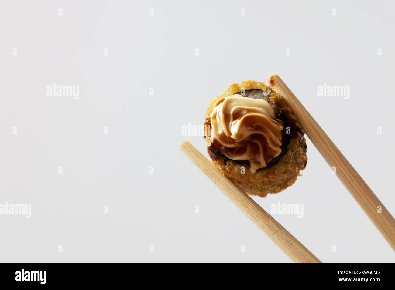 Zwei Essstäbchen mit einem heißen Brötchen, das mit Frischkäse und Tara-Sauce auf weißem Hintergrund bedeckt ist. Stockfoto