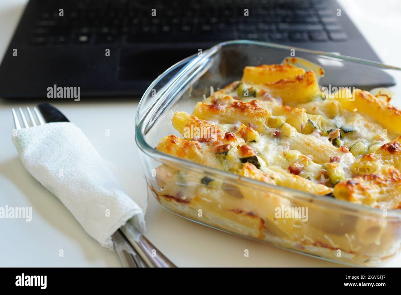 Mittagessen mit Pasta in Tupperware am Schreibtisch Stockfoto