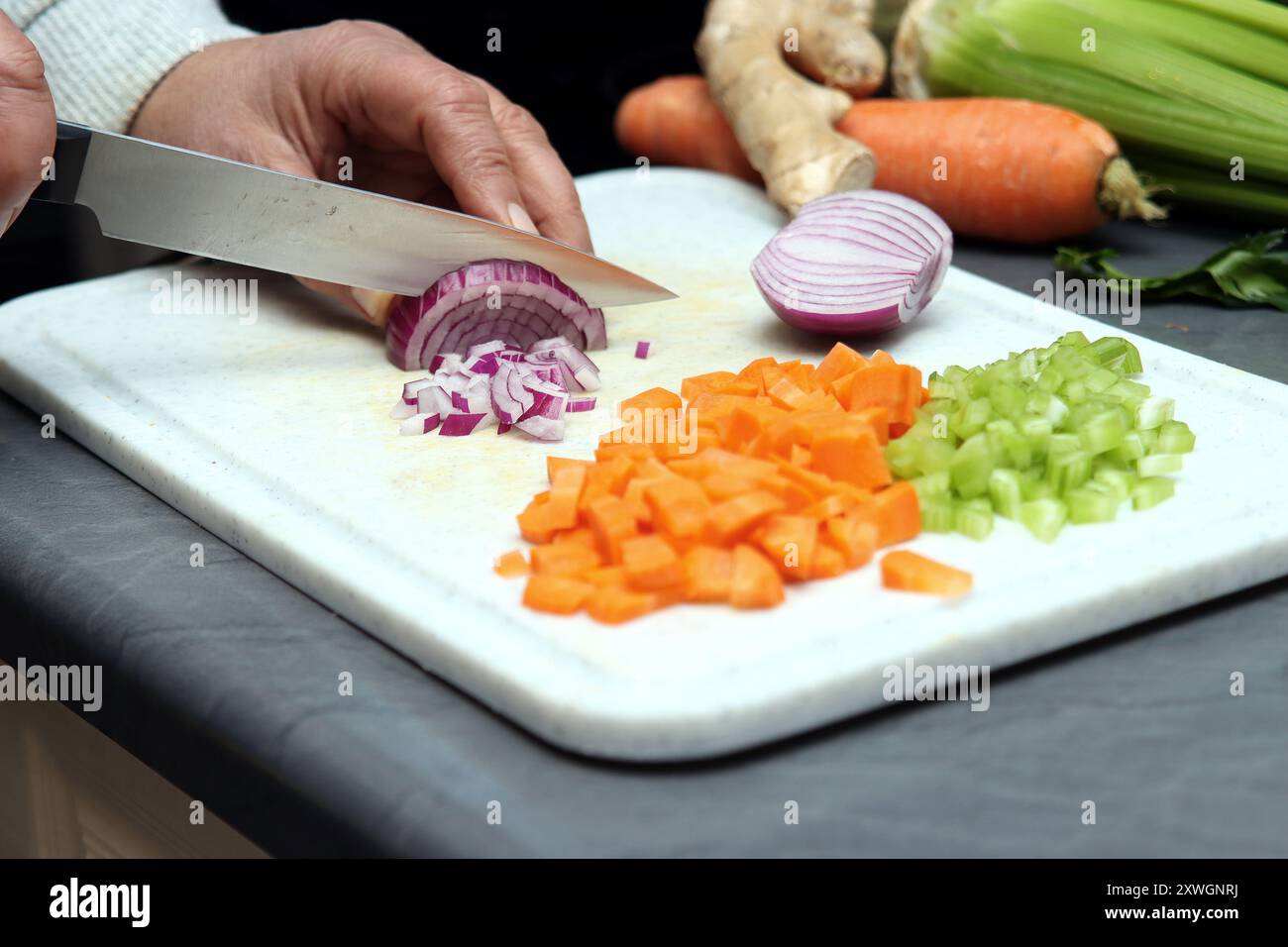 Frau schneidet Zwiebeln in kleine Würfel Stockfoto