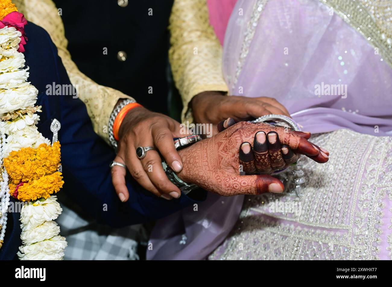 Der Bräutigam hält die Hand der Braut während einer hinduistischen Hochzeitszeremonie und konzentriert sich dabei auf komplexe kulturelle Aspekte Stockfoto