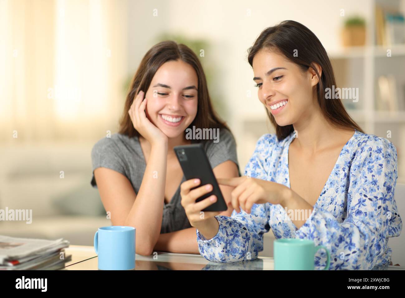 Glückliche Freunde, die zu Hause Telefoninhalte anschauen Stockfoto