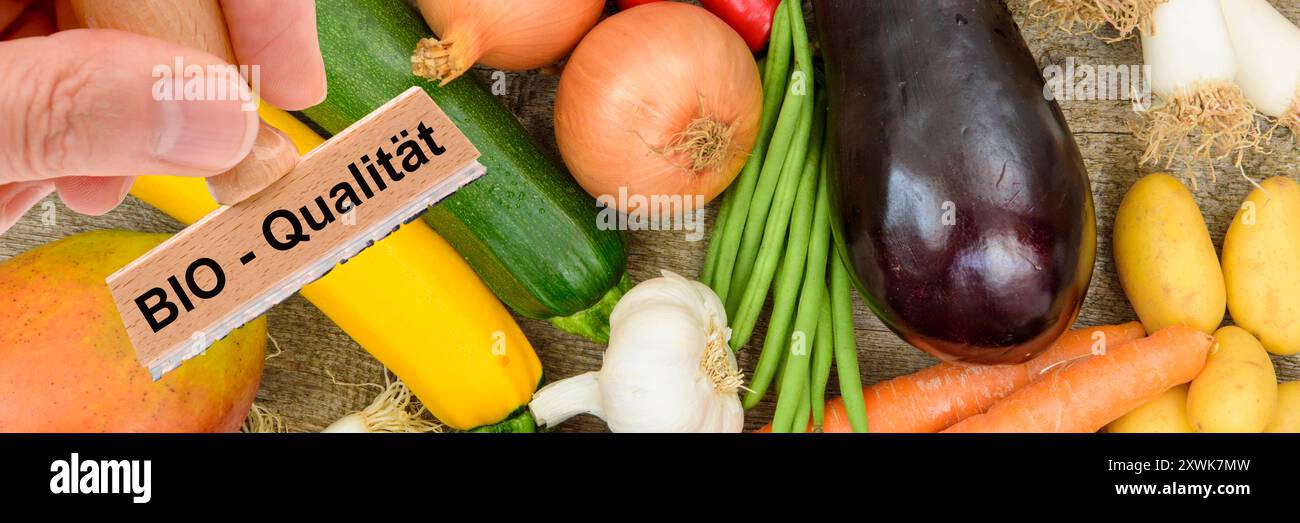 Bio-Qualität von Lebensmitteln ein Holzstempel ist beschriftet mit dem Aufdruck: Bio-Qualität über frisches Obst und Gemüse - FOTOMONTAGE *** Bio q Stockfoto