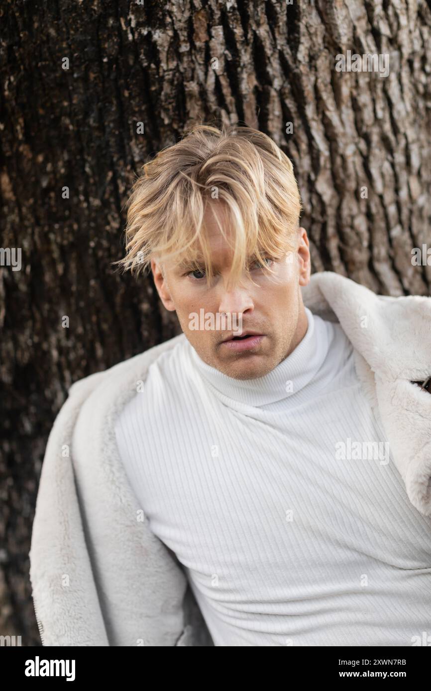 Ein stilvoller blonder Mann posiert in einem grünen Miami Park. Stockfoto