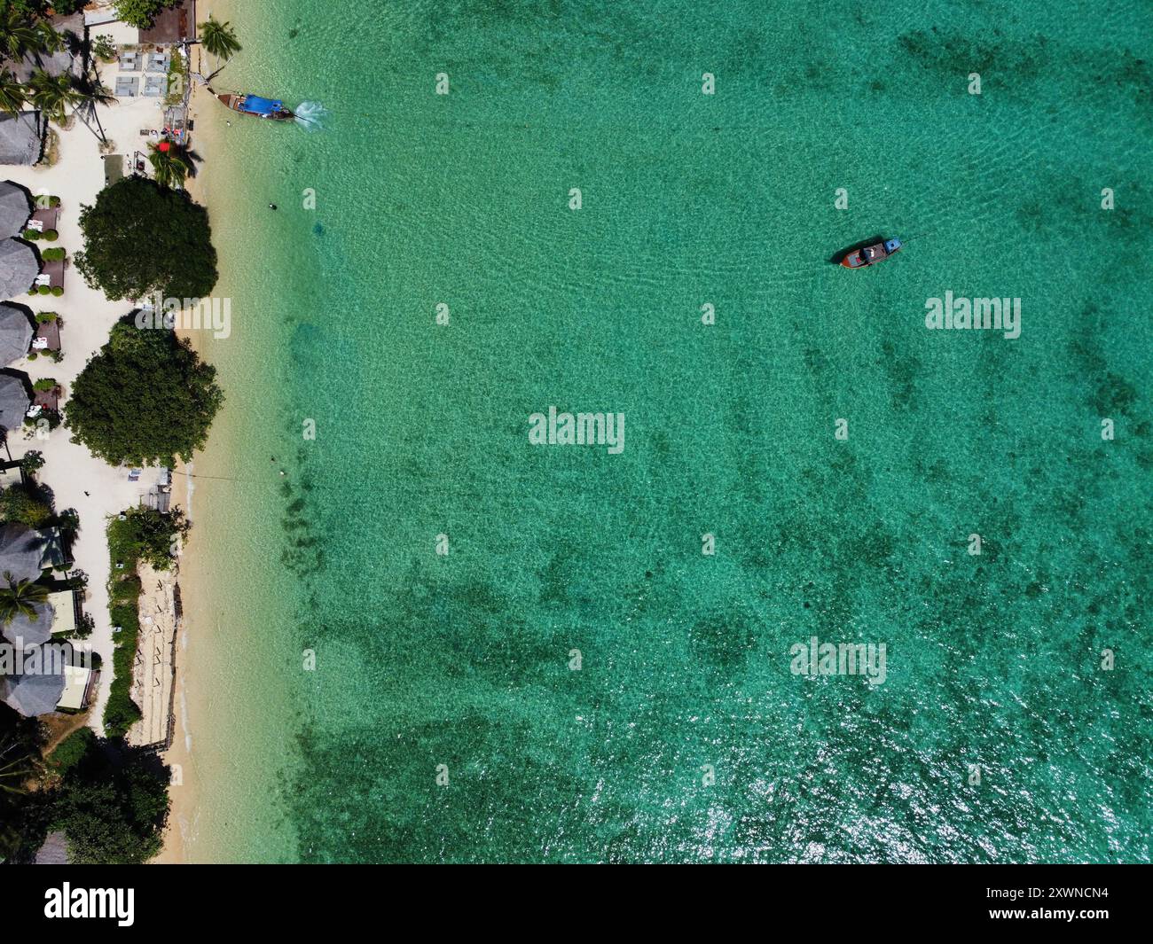 Blick von oben auf den Ko Ngai Strand mit weißem Sand, türkisfarbenem Wasser und langen Booten Stockfoto
