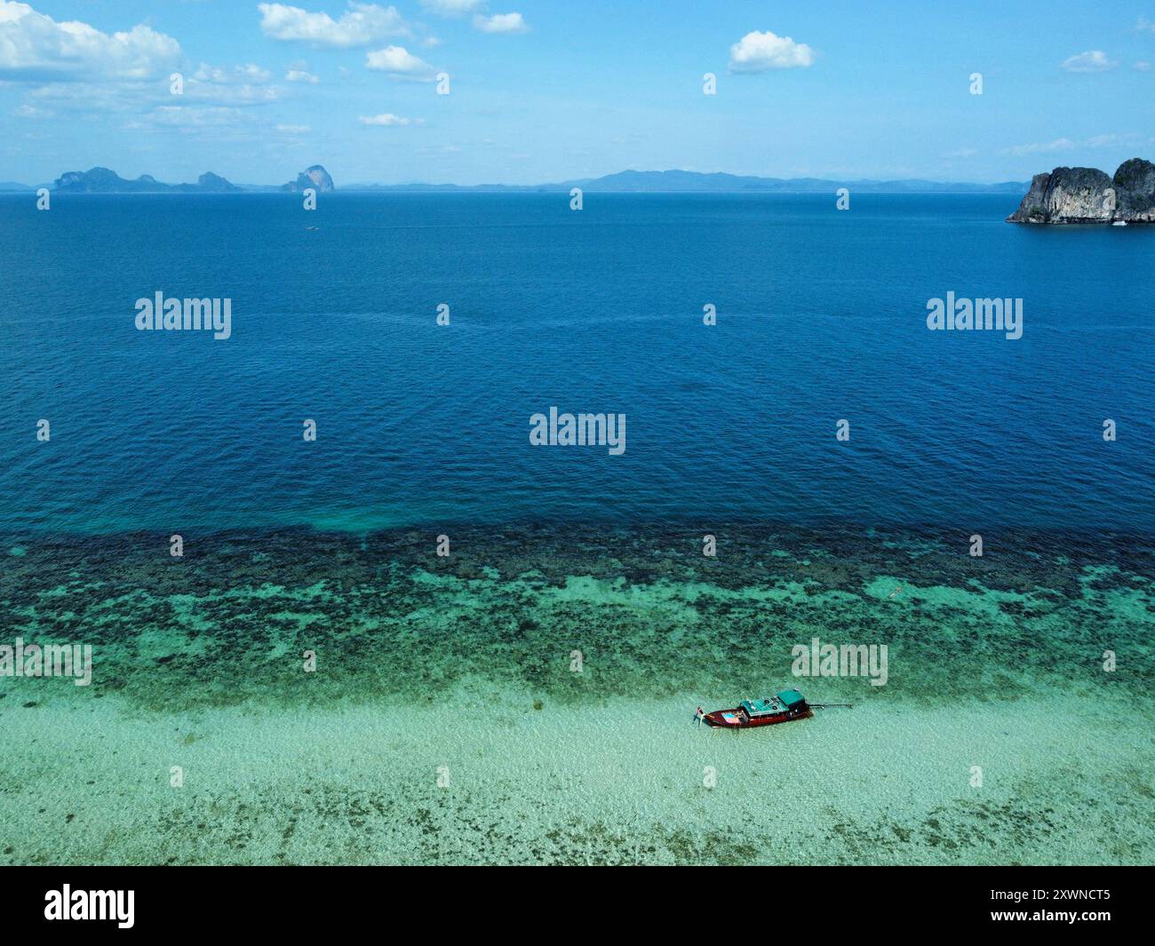 Aus der Vogelperspektive auf Ko Ngai bei Flut mit einem langen Boot über das türkisfarbene Wasser und die Insel Ko Maa im Hintergrund Stockfoto