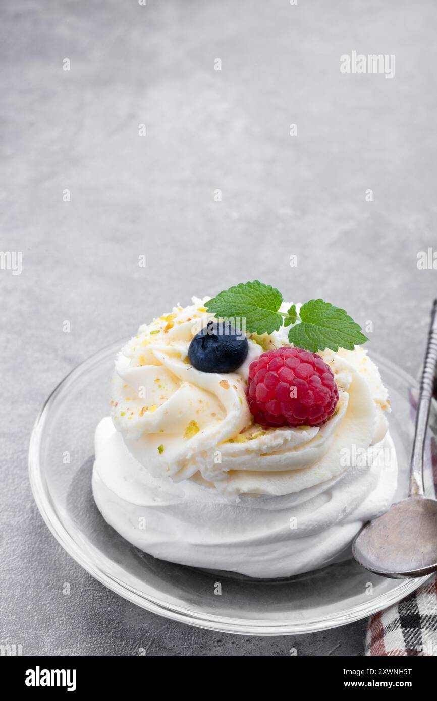 Mini Pavlova Meringue Nest mit Beeren und Schlagsahne auf grauem Hintergrund Stockfoto Mini Pavlova Meringue Nest mit Beeren und Schlagsahne auf grauem Hintergrund Stockfoto