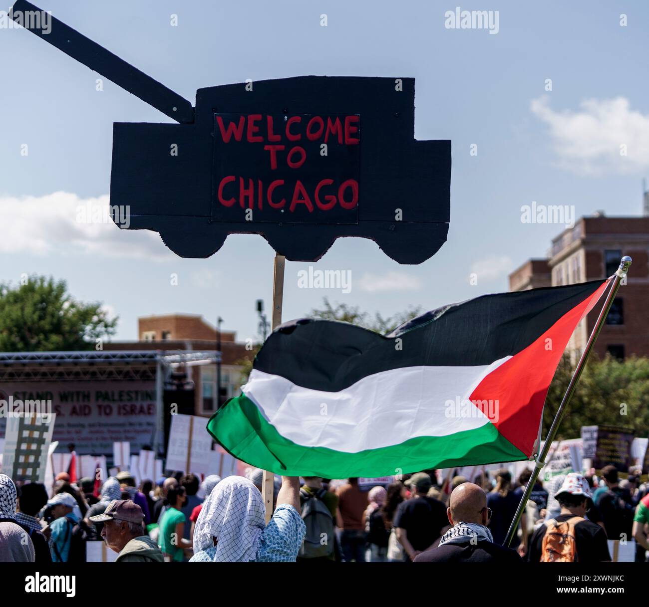 Chicago, Illinois, USA. August 2024. Auf einem Schild in Form eines Panzers steht „Willkommen in Chicago“, während die palästinensische Flagge darunter schwingt, während der Demonstration auf der DNC-Rallye im Union Park (Credit Image: © Chris Riha/ZUMA Press Wire) NUR REDAKTIONELLE VERWENDUNG! Nicht für kommerzielle ZWECKE! Stockfoto