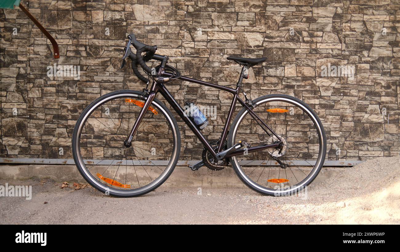 Rennrad gegen Steinmauer gelehnt. Rennrad parkte auf dem Bürgersteig. Städtisches Radfahren und umweltfreundliches Verkehrskonzept Stockfoto