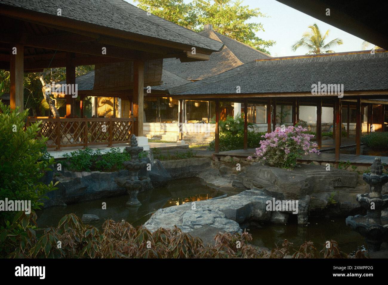 Nusa Dua, Bali, Indonesien - 19. August 2024 : Ein Gartenteich in einer Terrasse mit traditionellem japanischem Architekturhaus und einem Pavillon mit einem Holzwalkken Stockfoto