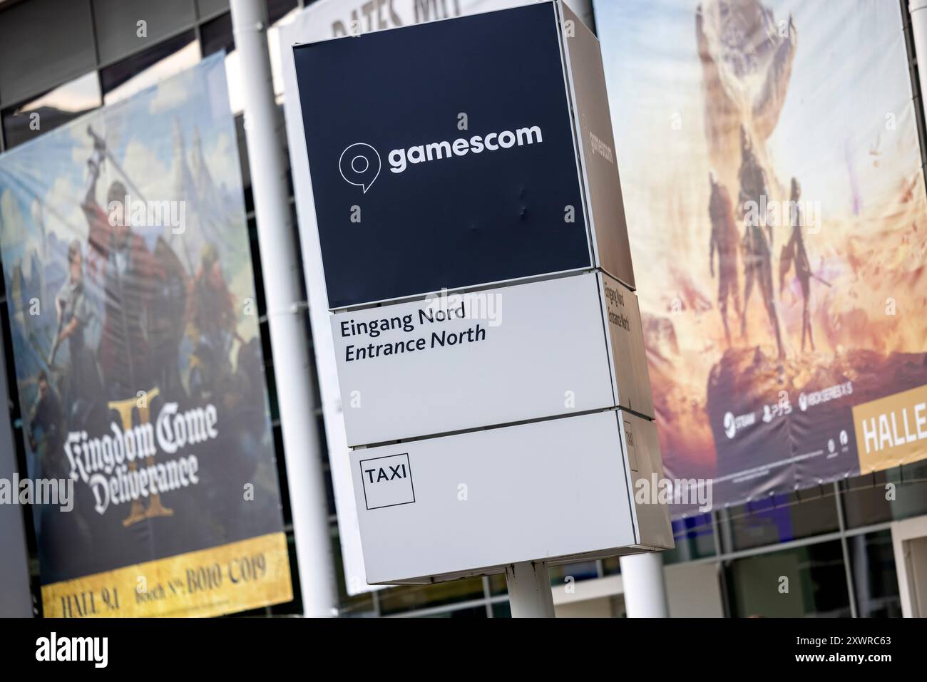 Köln, Deutschland. August 2024. Übergroße Plakate werben für Computerspiele vor dem Eingang zur Gamescom-Spielemesse. Hier findet die Eröffnungsshow am Abend statt. Die gamescom ist eine Messe für interaktive Unterhaltungselektronik, insbesondere Video- und Computerspiele, die vom 21. Bis 25. August in den Kölner Messehallen stattfindet. Quelle: Thomas Banneyer/dpa/Alamy Live News Stockfoto