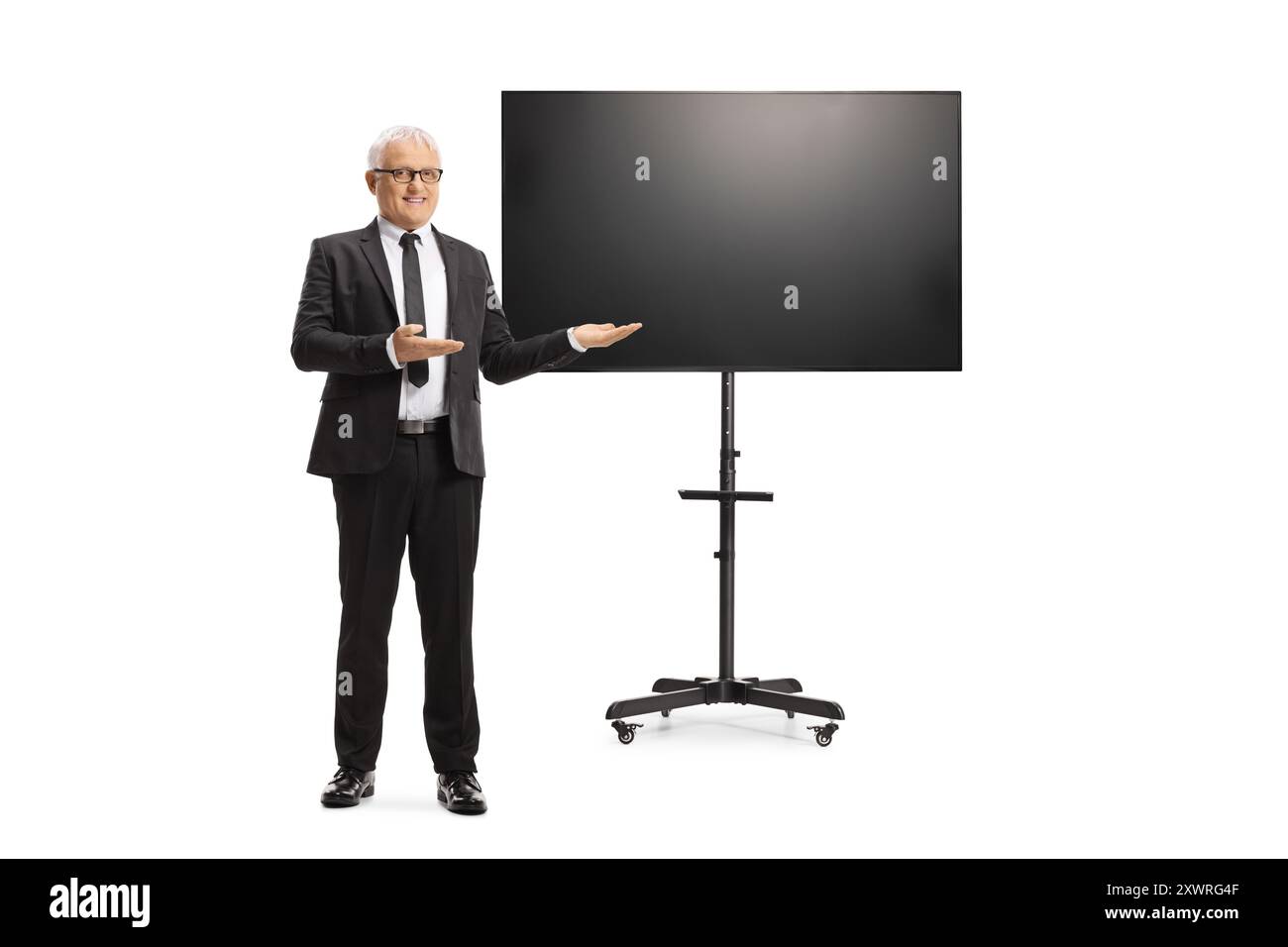 Porträt eines Geschäftsmannes mittleren Alters in voller Länge, der vor einem fernseher auf Ständer isoliert auf weißem Hintergrund präsentiert Stockfoto