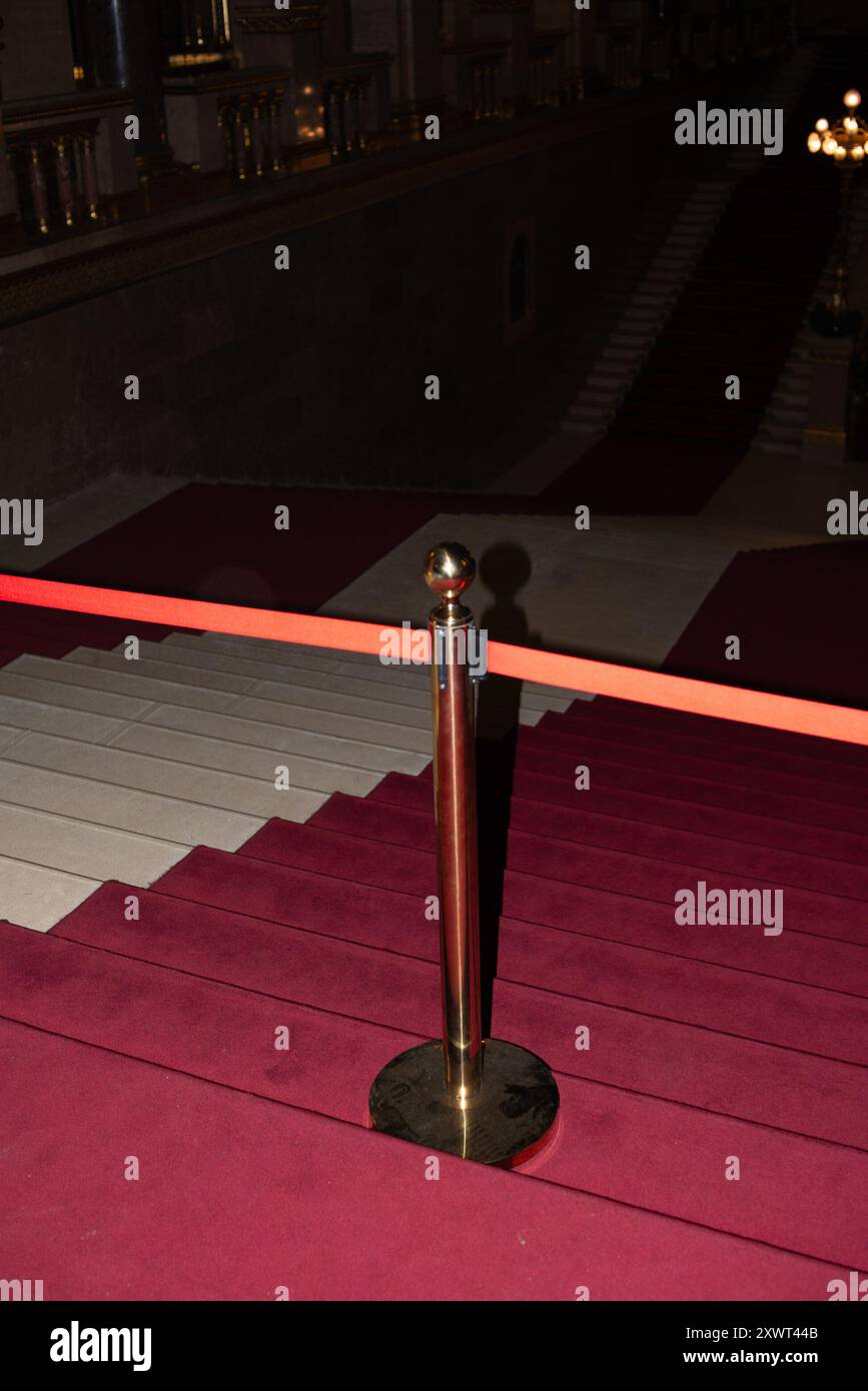 Im ungarischen Parlamentsgebäude ist eine Treppe mit rotem Teppich durch ein Samtseil begrenzt, was Exklusivität und Macht symbolisiert. Die historische Kulisse zeigt die Pracht der ungarischen Nationalversammlung. Stockfoto