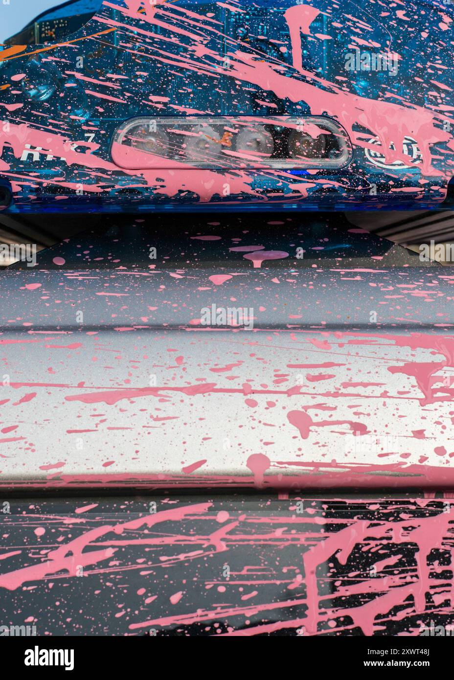 Nahaufnahme eines Polizeiautos, das nach Unruhen in Frankfurt schwer beschädigt und mit rosa Farbe bespritzt wurde. Das Bild symbolisiert Chaos, Protest und Bürgerunruhen. Stockfoto