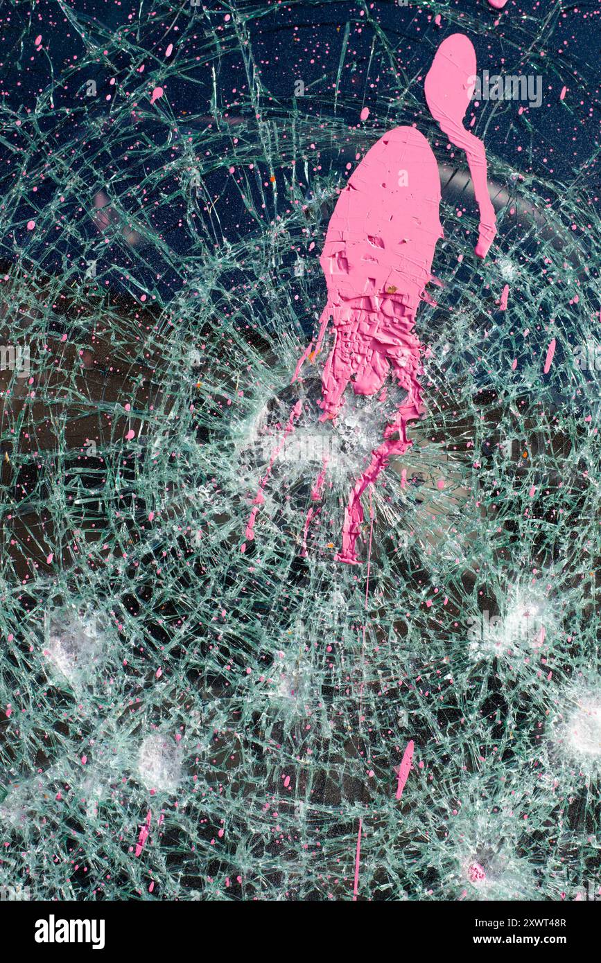 Nahaufnahme der zertrümmerten Windschutzscheibe eines zerrissenen Polizeiautos mit leuchtend rosa Farbspritzern, die Chaos und Zerstörung nach den Ausschreitungen in Frankfurt symbolisieren. Dieses Bild weckt Spannungen, Konflikte und Umbrüche. Stockfoto