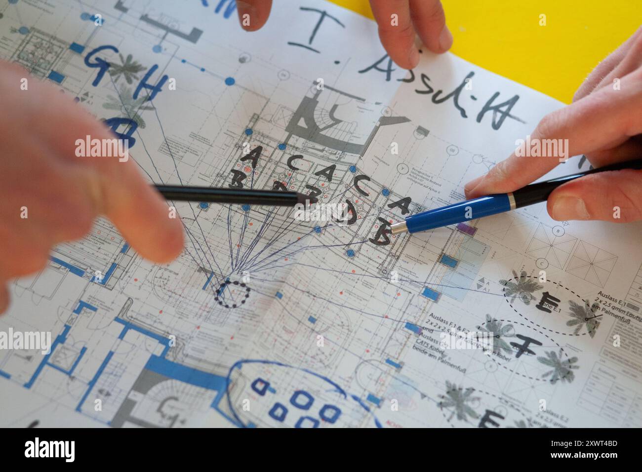 Nahaufnahme der Hände mit Stiften, um auf Details eines architektonischen Bauplans zu zeigen. Das Bild vermittelt Teamarbeit, Planung und Präzision, was eine Metapher für Zusammenarbeit und detailliertes Projektmanagement sein kann. Stockfoto