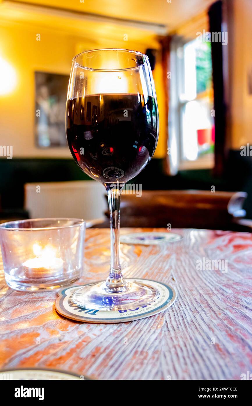 Großaufnahme eines Glases Rotwein auf Holztisch in einem gemütlichen britischen Pub Stockfoto