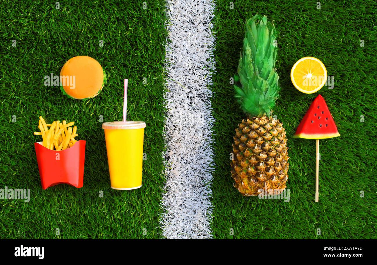 Auswahl an gesunden oder ungesunden Lebensmitteln - Burger, Pommes Frites, Saft, Ananas, Wassermelone auf Gras Stockfoto