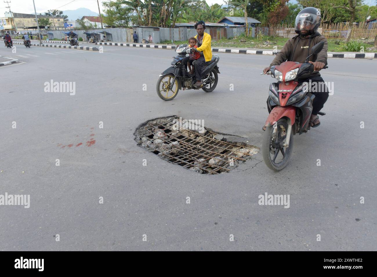 Wer in Wamena von der Hauptstraße in diese Seitenstraße abbiegt, muss aufpassen, keinen Unfall zu bauen. Unter dem Asphalt verläuft ein Abwasserkanal und die Teerdecke ist an einer Stelle durchbrochen. *** Wer von der Hauptstraße in diese Seitenstraße in Wamena abzweigt, muss darauf achten, dass Er keinen Unfall verursacht. Ein Kanalkanal läuft unter dem Asphalt und die Teeroberfläche ist an einer Stelle gebrochen Stockfoto