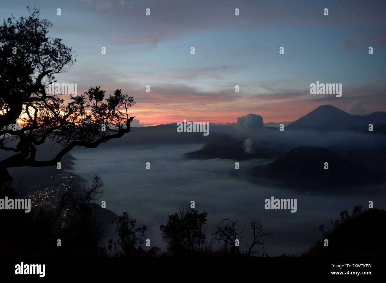 Frühnebel bei Sonnenaufgang in der Tengger-Caldera. Im Hintergrund ist der Vulkan Semeru, mit 3676 m Höhe der höchste Berg der indonesischen Insel Java, zu sehen. Der Nationalpark Bromo-Tengger-Semeru besteht seit 1982. Der mittlere Teil des Namens verweist auf das hier lebende Volk der Tengger. Zum Nationalpark gehören der 3676 m hohe Stratovulkan Semeru, der höchste Berg der Insel, sowie vier in der Tengger-Caldera liegende Vulkane, deren Bekanntester der Bromo ist. Die Caldera wird vom Tengger-Sandmeer malaiisch: Laut Pasir Tengger ausgefüllt. Vier gesehen und etwa 50 Flüsse liegen auf dem Ter Stockfoto