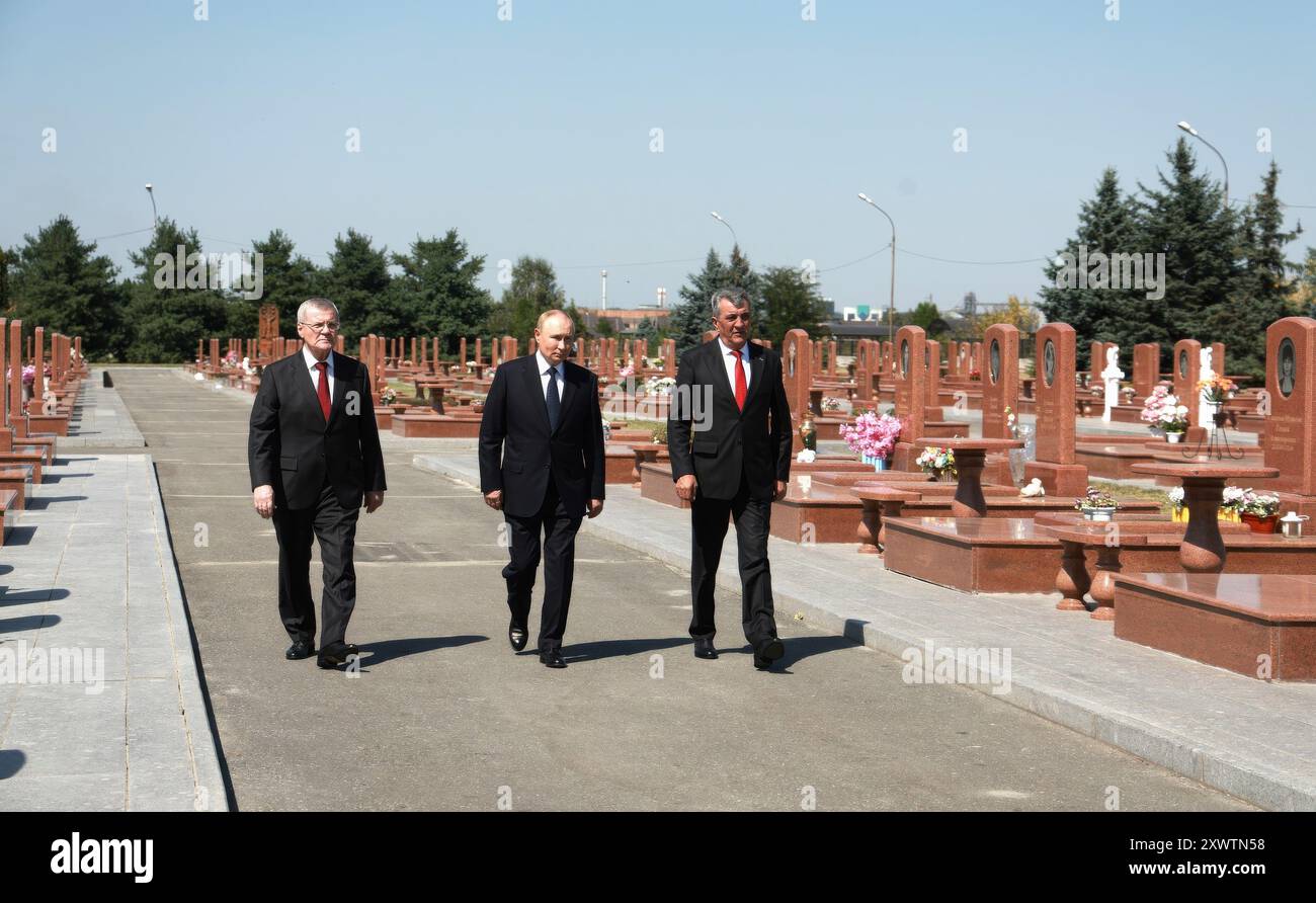 Beslan, Russland. August 2024. Der russische Präsident Wladimir Putin, Mitte, begleitet von Nordossetien-Alania-Chef Sergei Menyailo, links, und der nordkaukasische Bundesbezirksgesandte Juri Chaika, zollt seinen Respekt auf dem Gedenkfriedhof der Stadt der Engel, 20. August 2024 in Beslan, Republik Nordossetien-Alanien, Russland. Beslan ist der Schauplatz der tödlichsten Schulschießerei der Geschichte, die mit dem Tod von 334 Menschen endete. Quelle: Vyacheslav Prokofyev/Kreml Pool/Alamy Live News Stockfoto