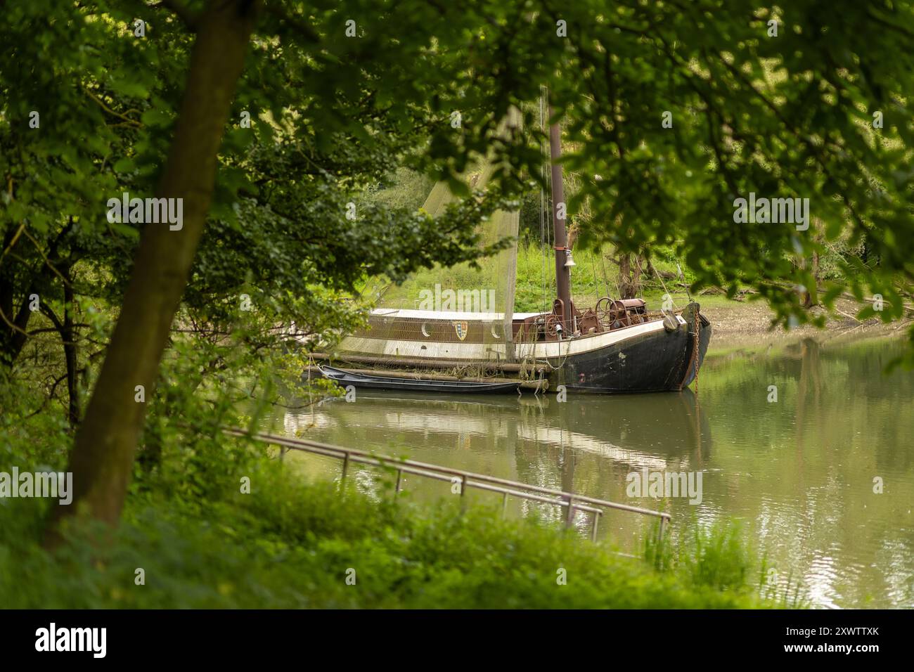 Ein Boot ruht ruhig auf dem Wasser, umgeben von lebendigem Laub, und schafft eine ruhige Atmosphäre entlang des Flusses. Stockfoto