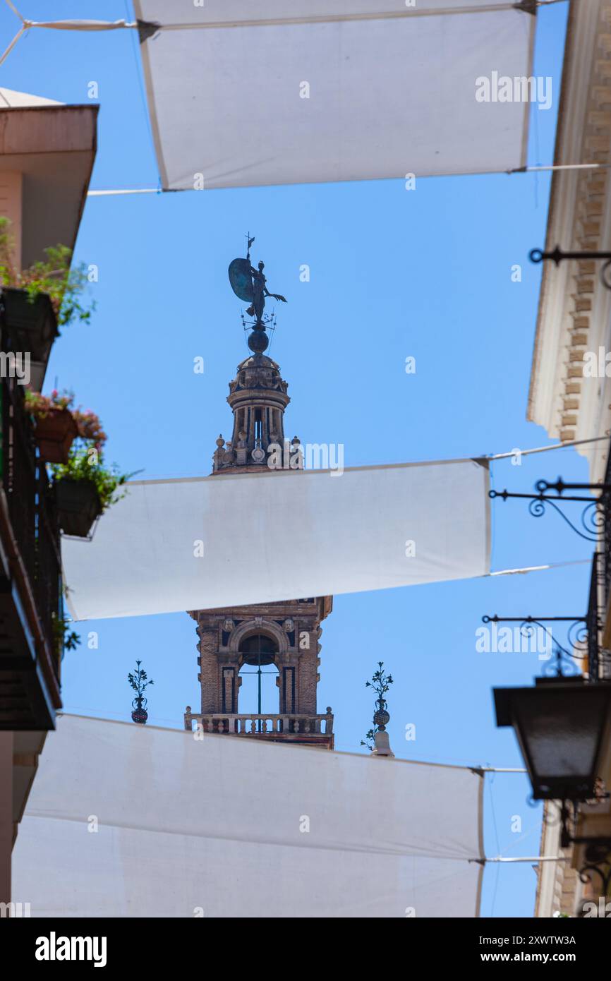 El Giraldillo, die Statue auf der Spitze der Giralda, der Glockenturm der berühmten Kathedrale von Sevilla von der Straße aus gesehen, Andalusien, Spanien Stockfoto