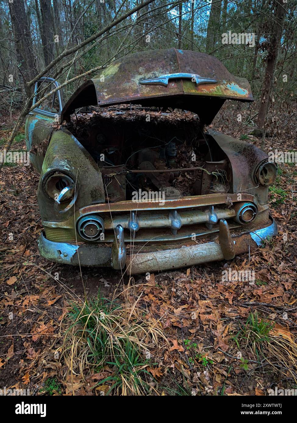 Ein verlassenes Auto wurde im Wald neben einer Kirche gefunden. Stockfoto