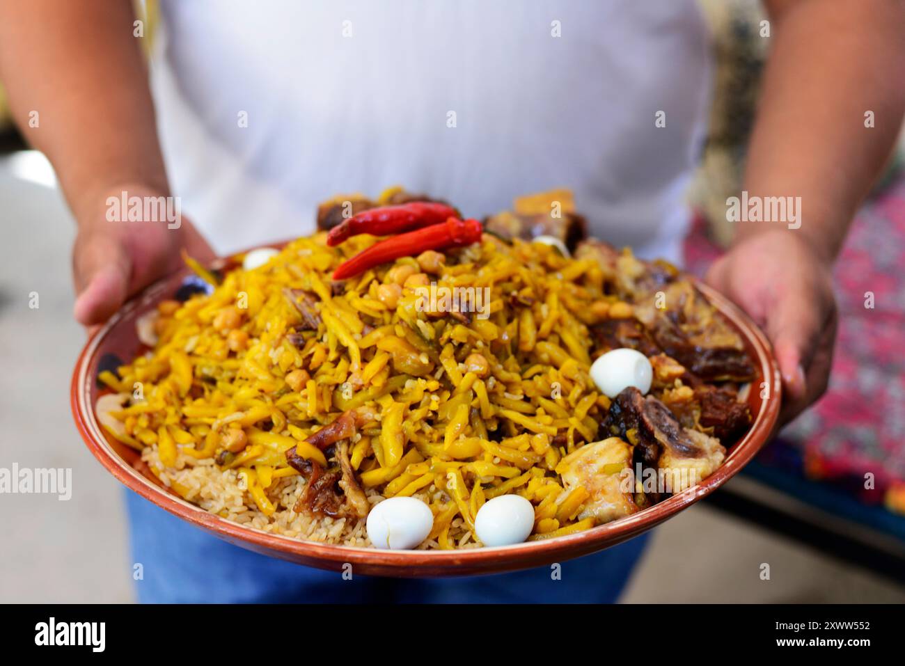 Plov ist das Nationalgericht Usbekistans. Ein usbekischer Mann mit einem Teller traditioneller Plov in einem kleinen Restaurant in Samarkand, Usbekistan. Stockfoto