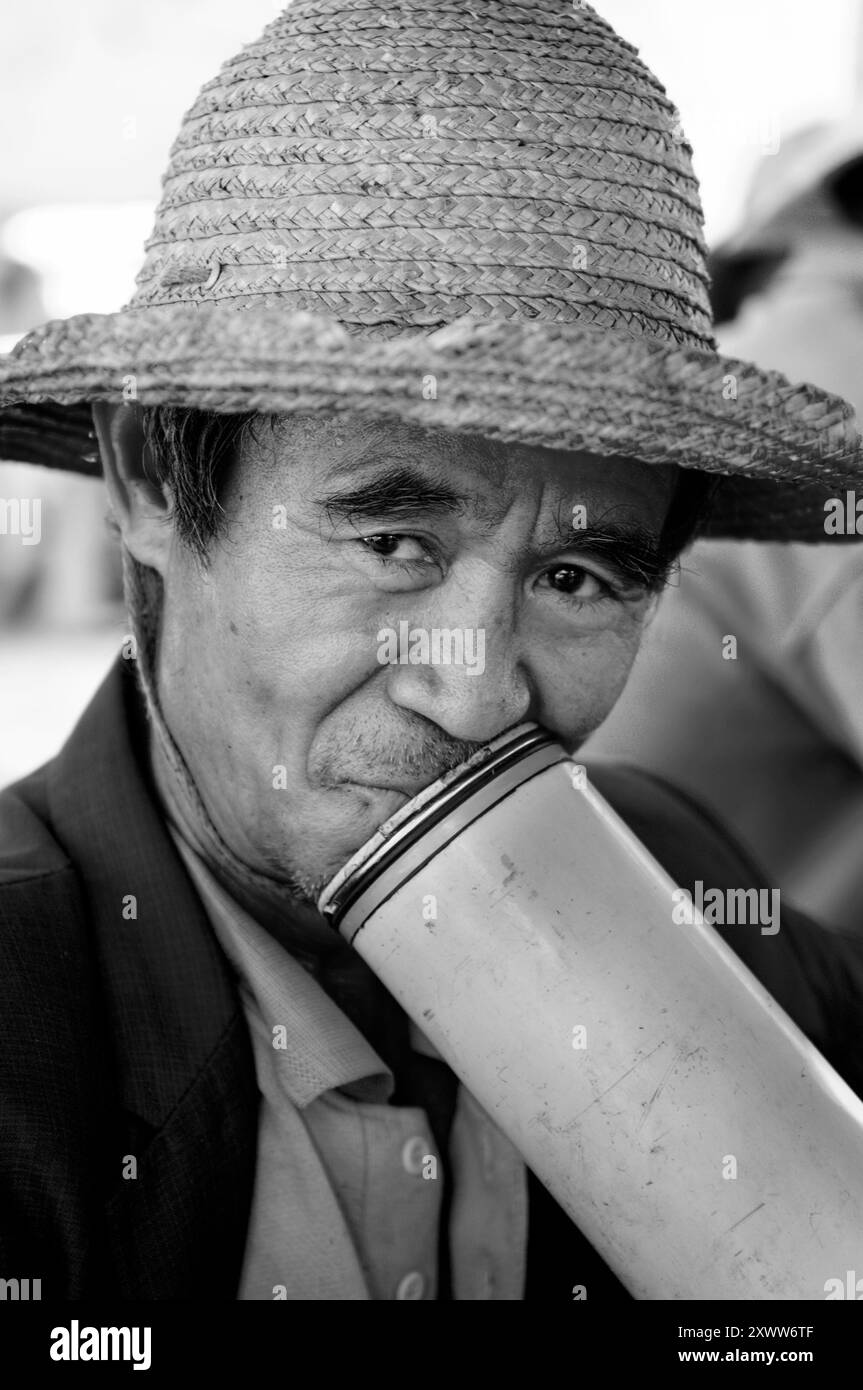 Rauch am Nachmittag mit einer traditionellen Bambuspfeife. Foto auf einem Wochenmarkt in der Provinz Yunnan, China. Stockfoto