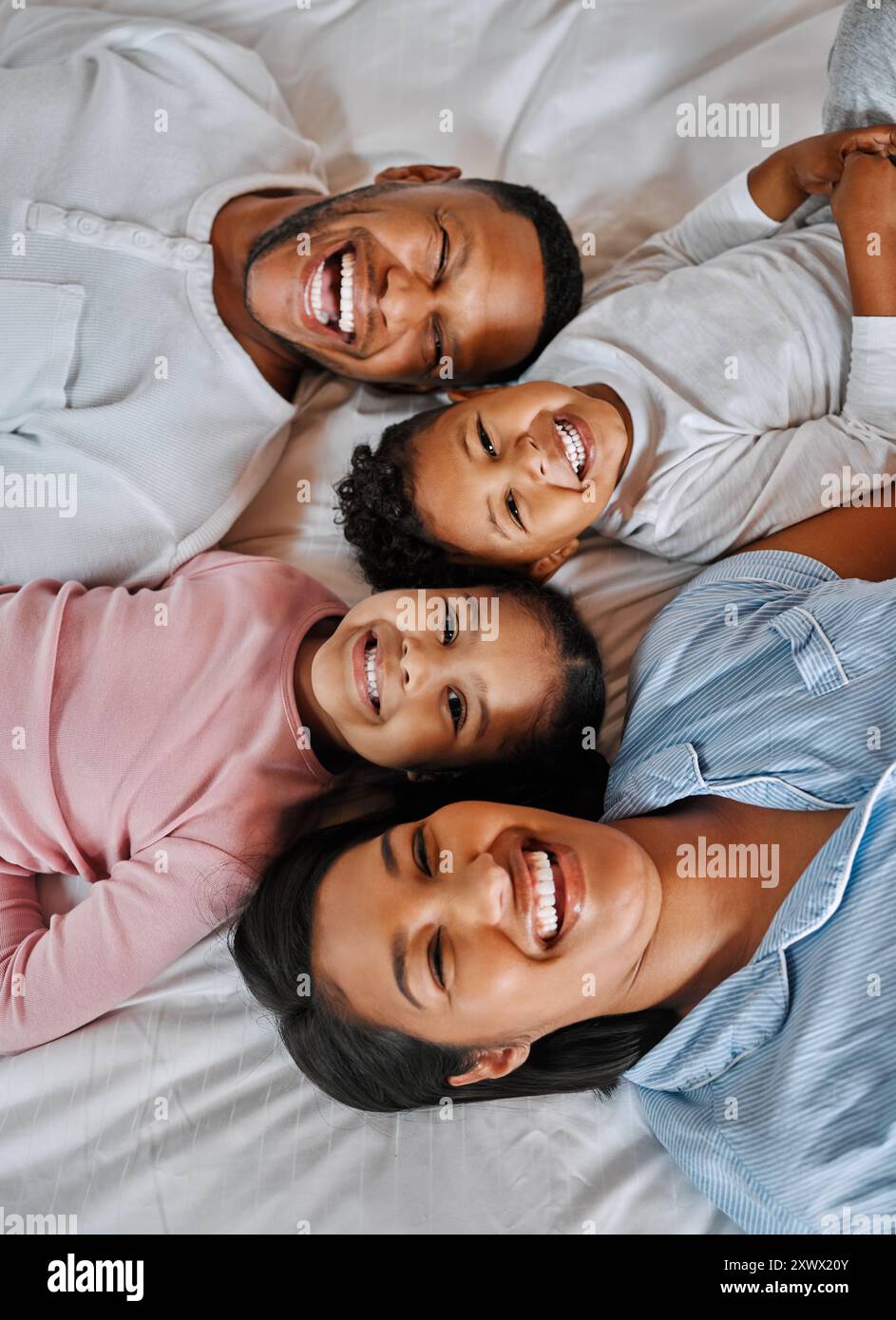 Mama, Vater und Kinder im Porträt auf dem Bett mit Lächeln, Liebe und Entspannung am Morgen zusammen von oben. Mutter, Vater und Kinder, die sich im Schlafzimmer verbünden Stockfoto