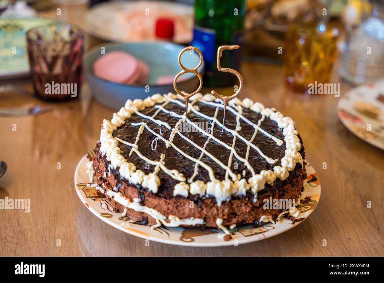 Eine Nahaufnahme eines hausgemachten Schokoladenkuchens mit glatter weißer Creme in gemütlicher Atmosphäre. Der Kuchen ist mit Glitzern geschmückt, die in die Form geformt sind Stockfoto