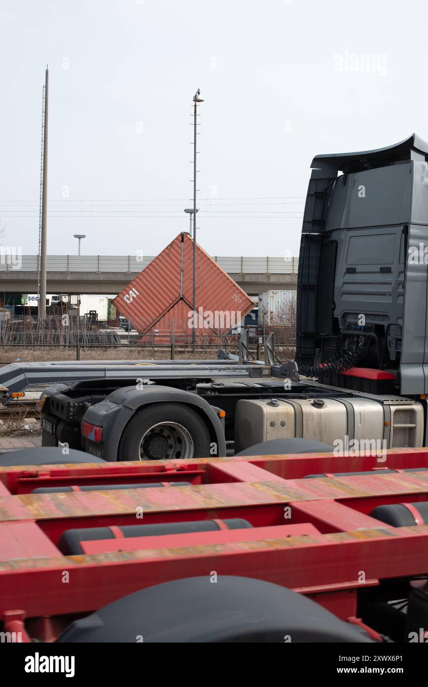 Eine detaillierte Ansicht eines Industriegebiets in Manheim, Deutschland, mit Transportelementen, einschließlich Lkw und einem Versandcontainer. Die Szene beleuchtet Logistik, Industrietransport und Infrastruktur und vermittelt ein Gefühl von Bewegung und Effizienz. Stockfoto