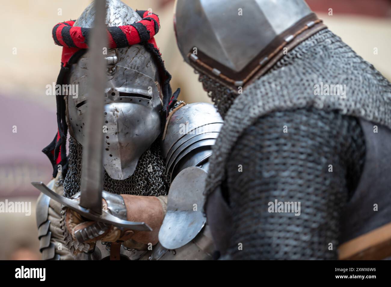 Jaunpils, Lettland – 10. August 2024: Zwei gepanzerte Ritter kämpfen mit Schwertern bei einer Nachstellung. Stockfoto