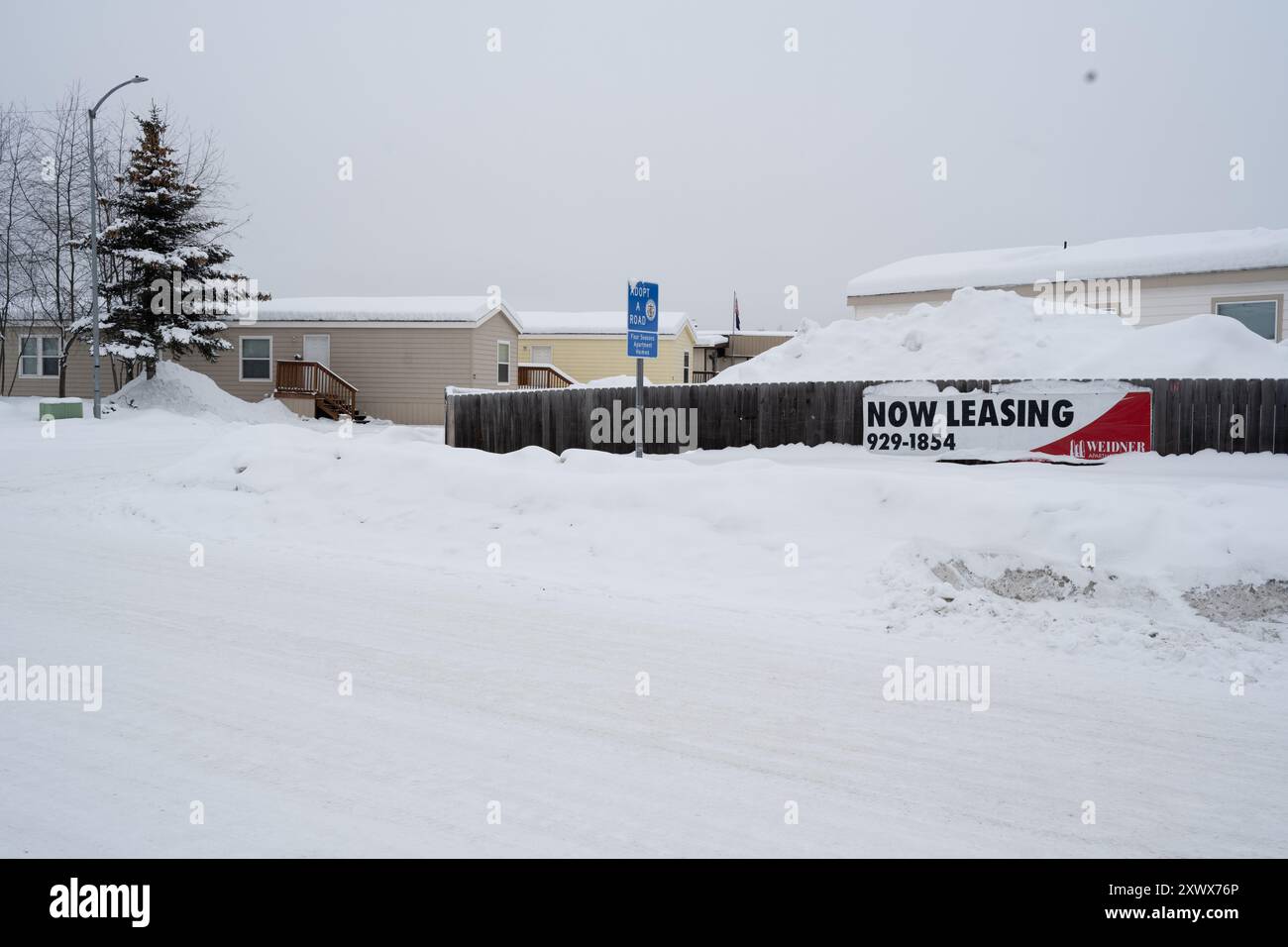 Ein Wohnwagenpark in Anchorage, Alaska, der im Winter mit Schnee bedeckt ist. Das Foto zeigt ein „Now Leasing“-Schild, schneebedeckte Mobilheime und eine ruhige Winterumgebung. Ideal für Themen wie Winter, Wohnraum und Alaska. Stockfoto