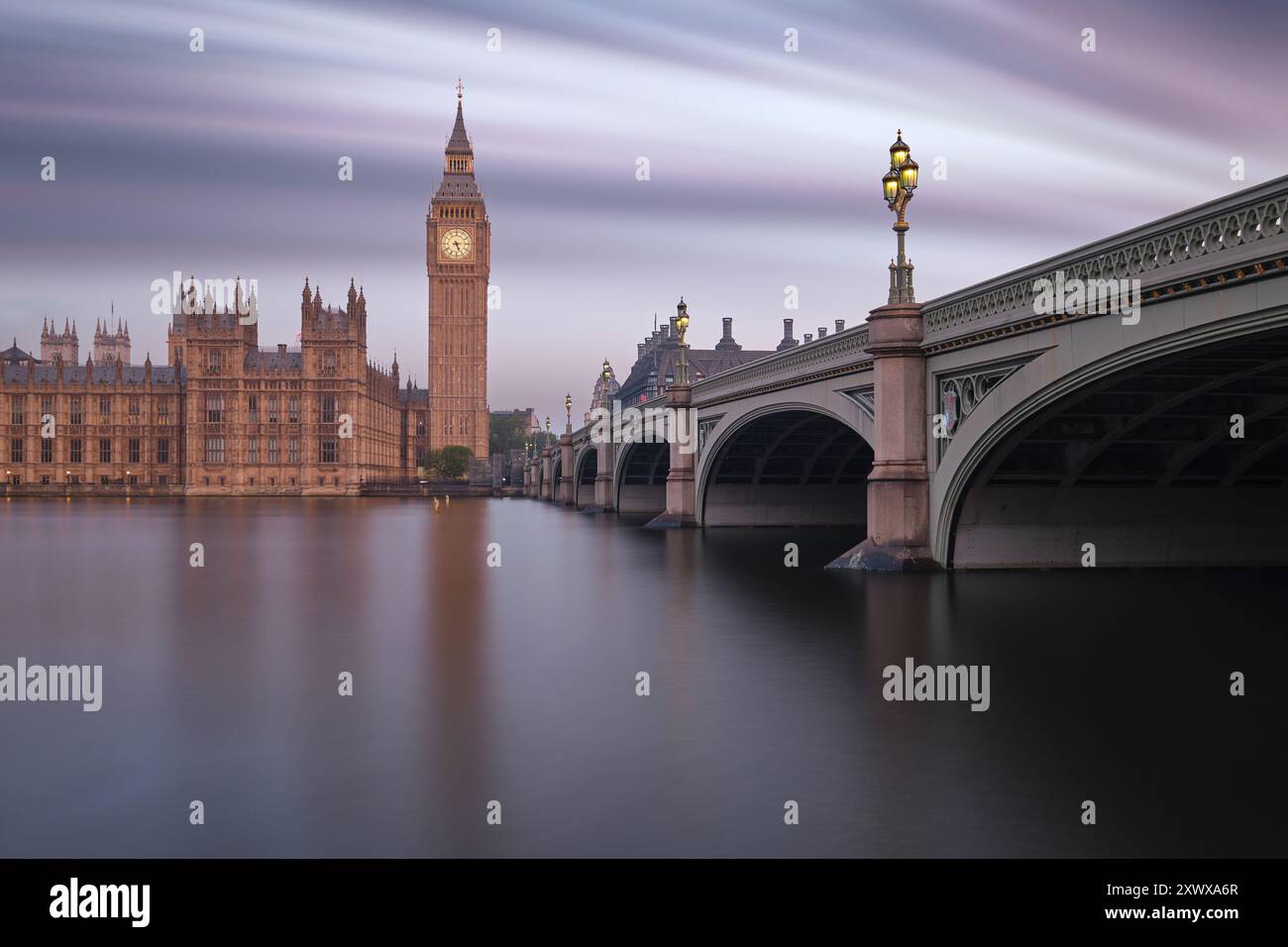 Atemberaubende Langzeitbelichtung von Big Ben und Westminster Bridge bei Sonnenaufgang, die die ruhige Schönheit von Londons berühmten Wahrzeichen in sanftem, ruhigem Licht einfangen lässt Stockfoto