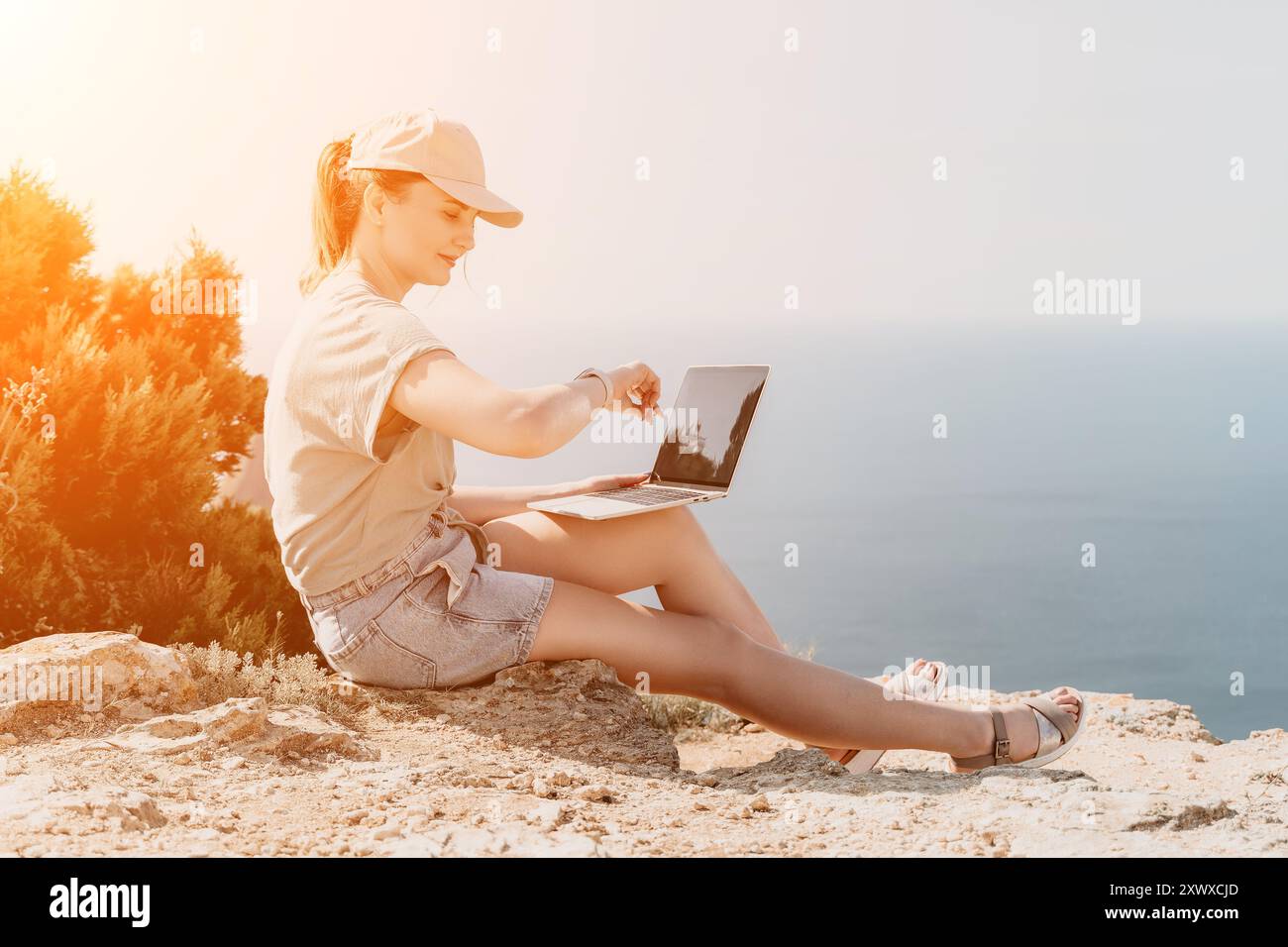 Frau, die an Laptop am Meer arbeitet Stockfoto